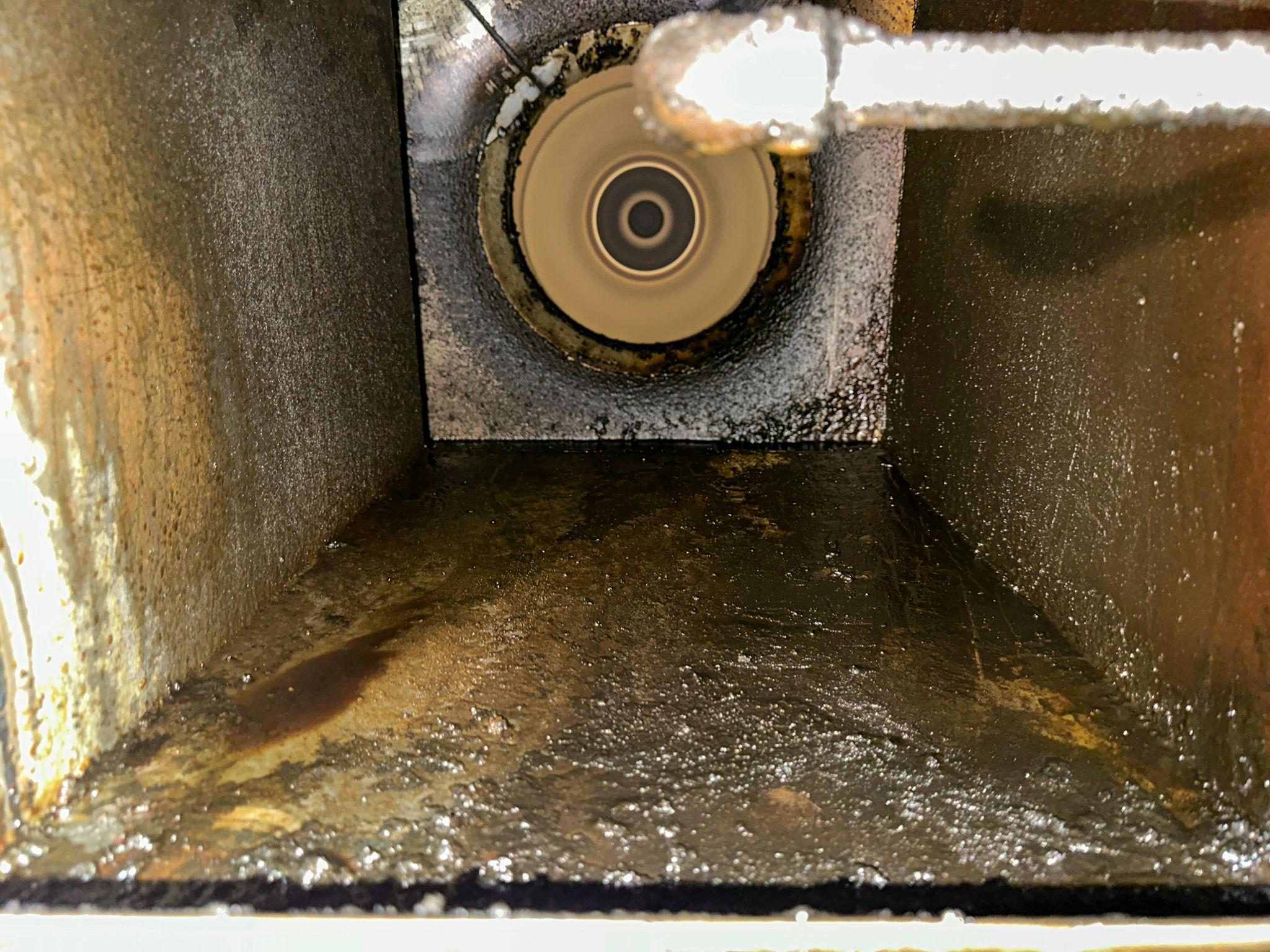 Heavy grease buildup inside a commercial kitchen exhaust duct before professional cleaning.
